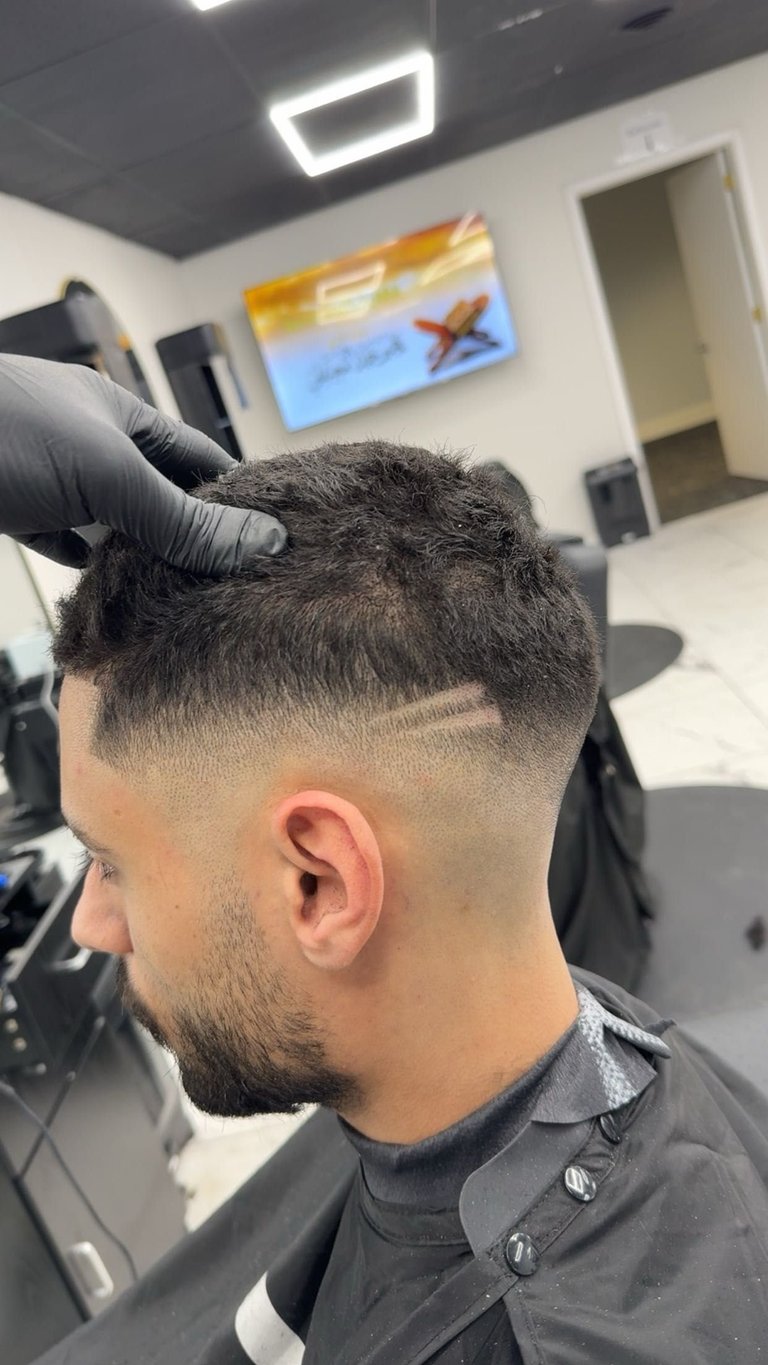 Barber styling short faded haircut on male client in modern salon with neon lighting and beach artwork